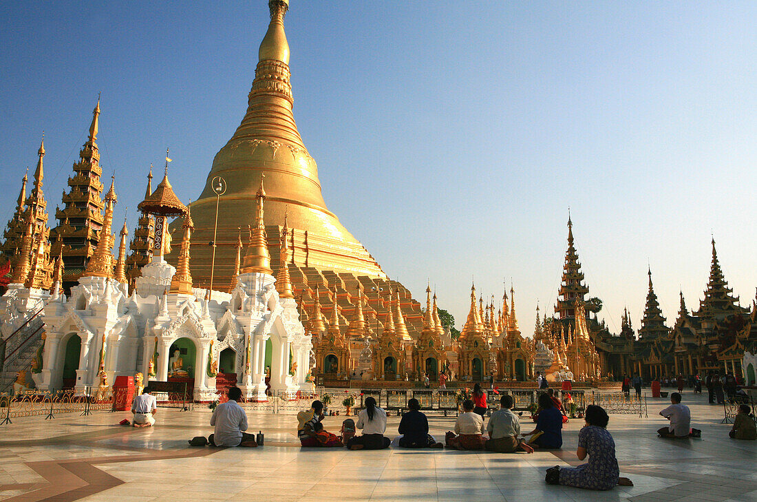 Praying buddhists at the Shwedagon Pagoda in the light of the evening sun, Rangoon, Myanmar, Burma, Asia
