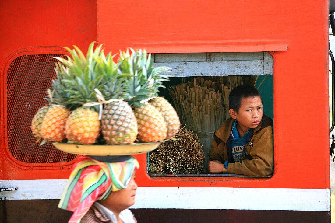 Eine Frau verkauft Obst, ein Junge schaut aus dem Fenster eines Zuges, Hispaw, Shan Staat, Myanmar, Birma, Asien