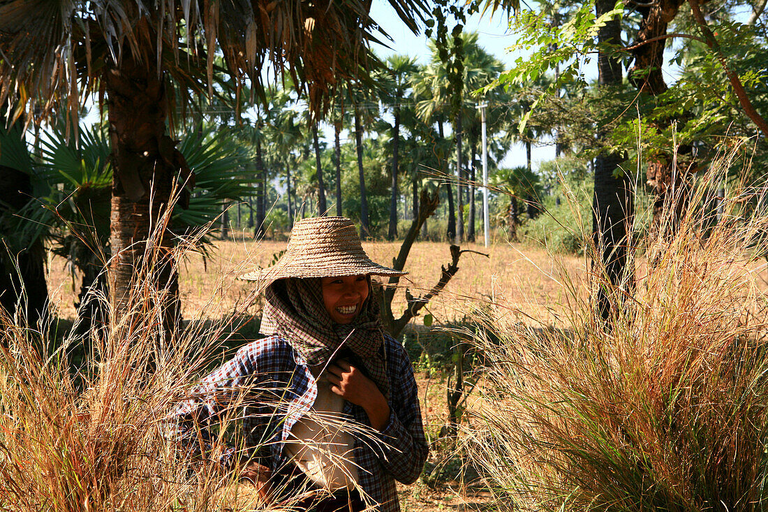 Lachende Frau mit Hut zwischen Palmen, Myanmar, Birma, Asien