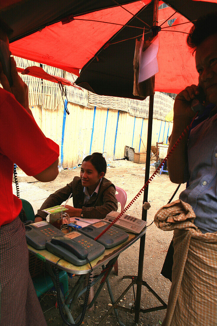 Eine junge Frau unter einem Sonnenschirm vermietet Telefone, Rangoon, Myanmar, Birma, Asien
