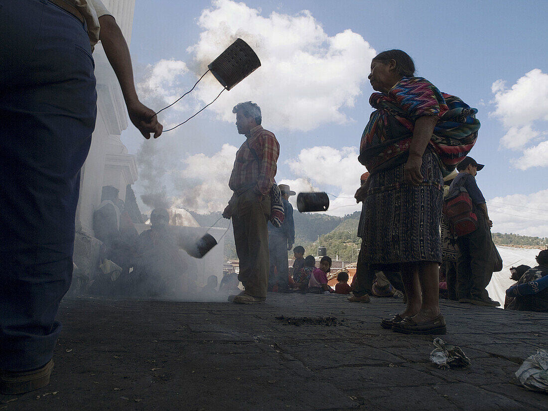 Worshippers swinging incense burning in cans outsiude church in Chichicastenango, Guatemala