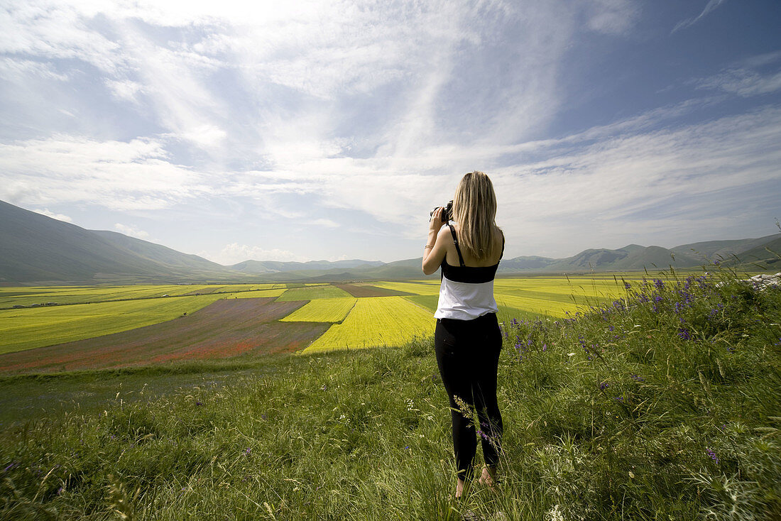 Italy  Umbria  Norcia  Highland of Castelluccio di Norcia  Woman taking pictures of Lentils Fields