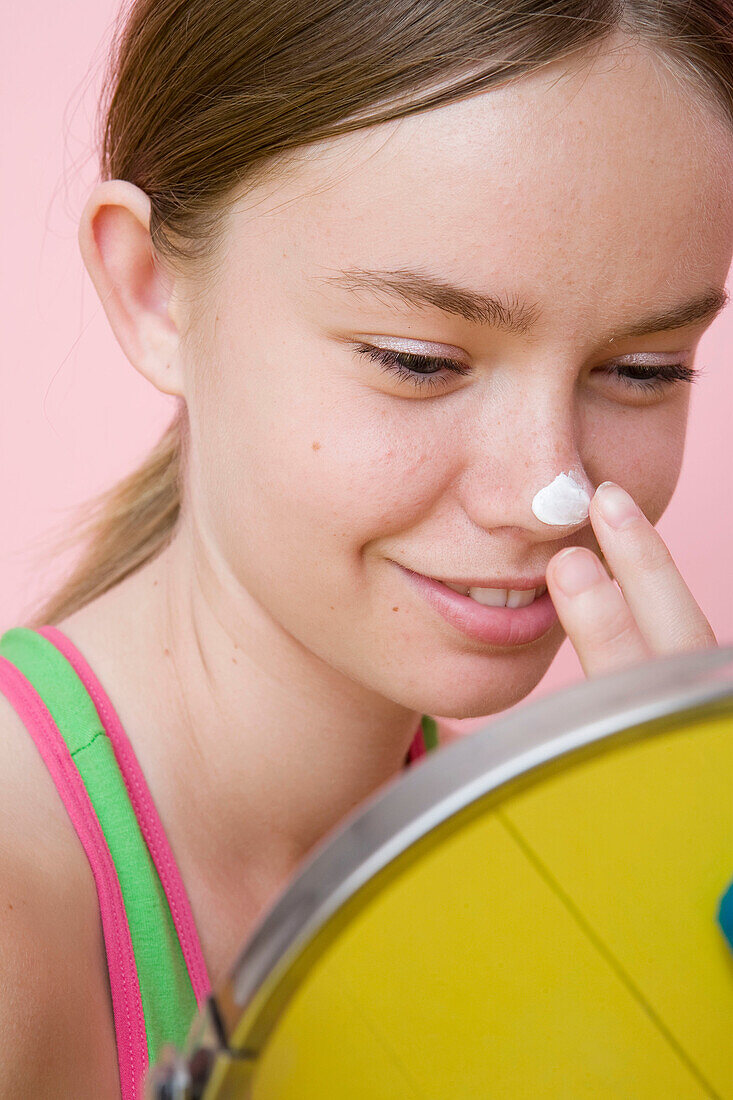 Junge Frau mit Gesichtscreme auf der Nase