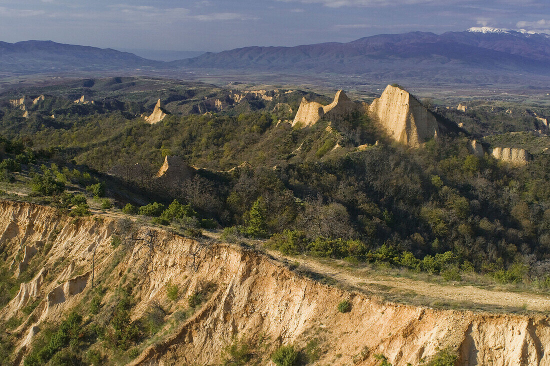 Hoodoo rocks of Melnik, geologic formations of soft sedimentary rocks, overlooking cultivated  landscape of Bistrica and Struma Valley, Bulgarian-Greek border mountains with snow-covered Radomir, South Bulgaria