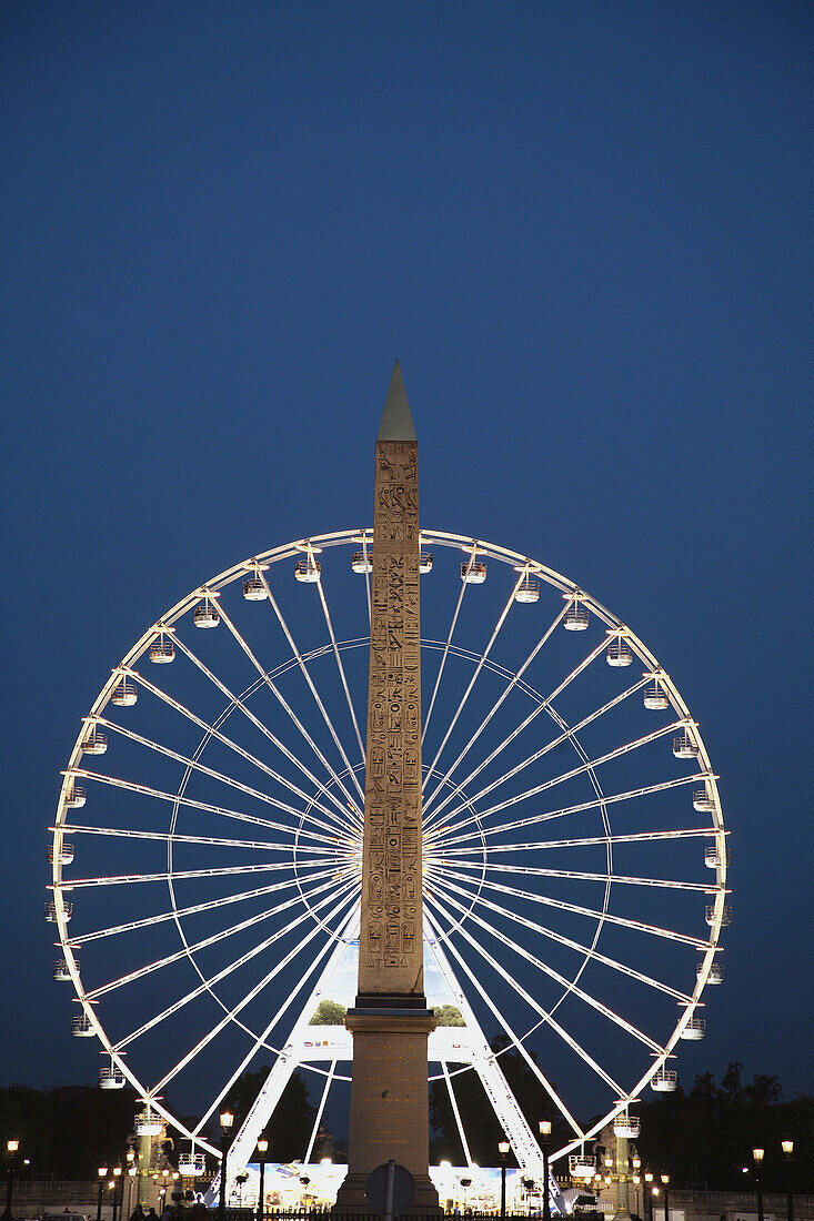 France. Paris. The night view of 3200 years old obelisk from Luxor in Palace de la Concorde with ferry wheel in the background.