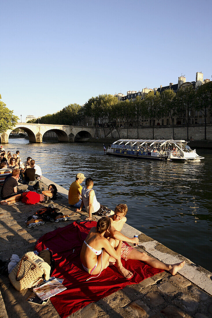 France. Paris. People relax in later afternoon sun light during Paris Plage along the bank of River Seine.