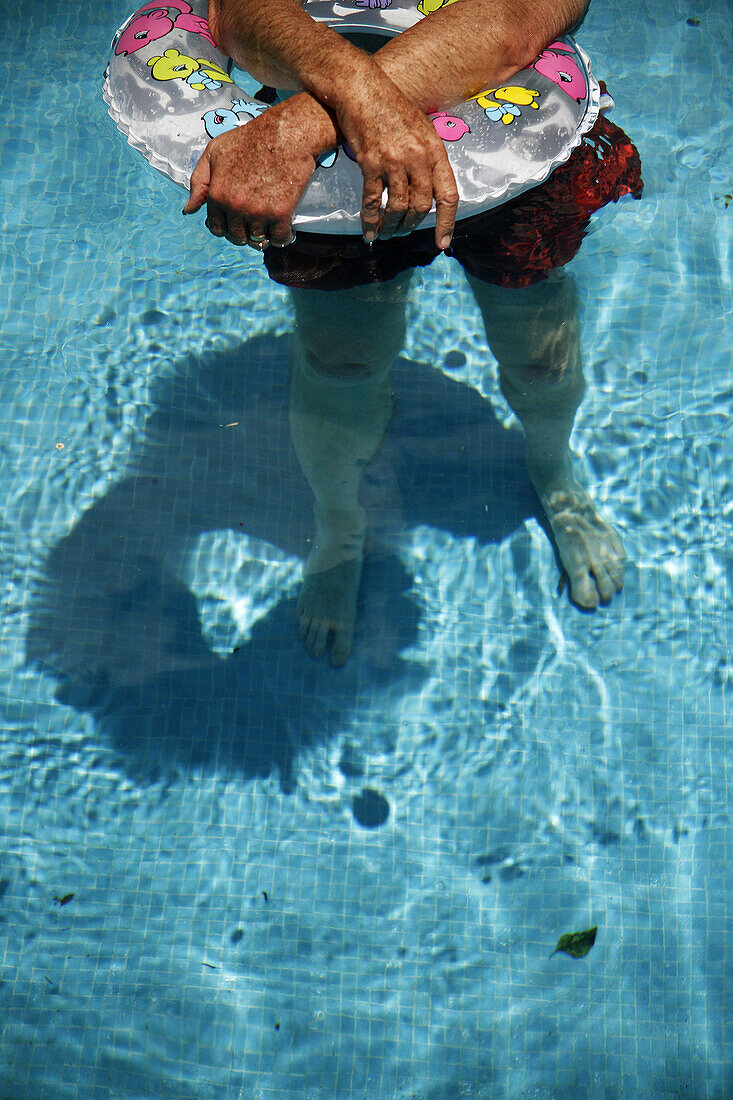 Man with an inflatable in a swimming pool.