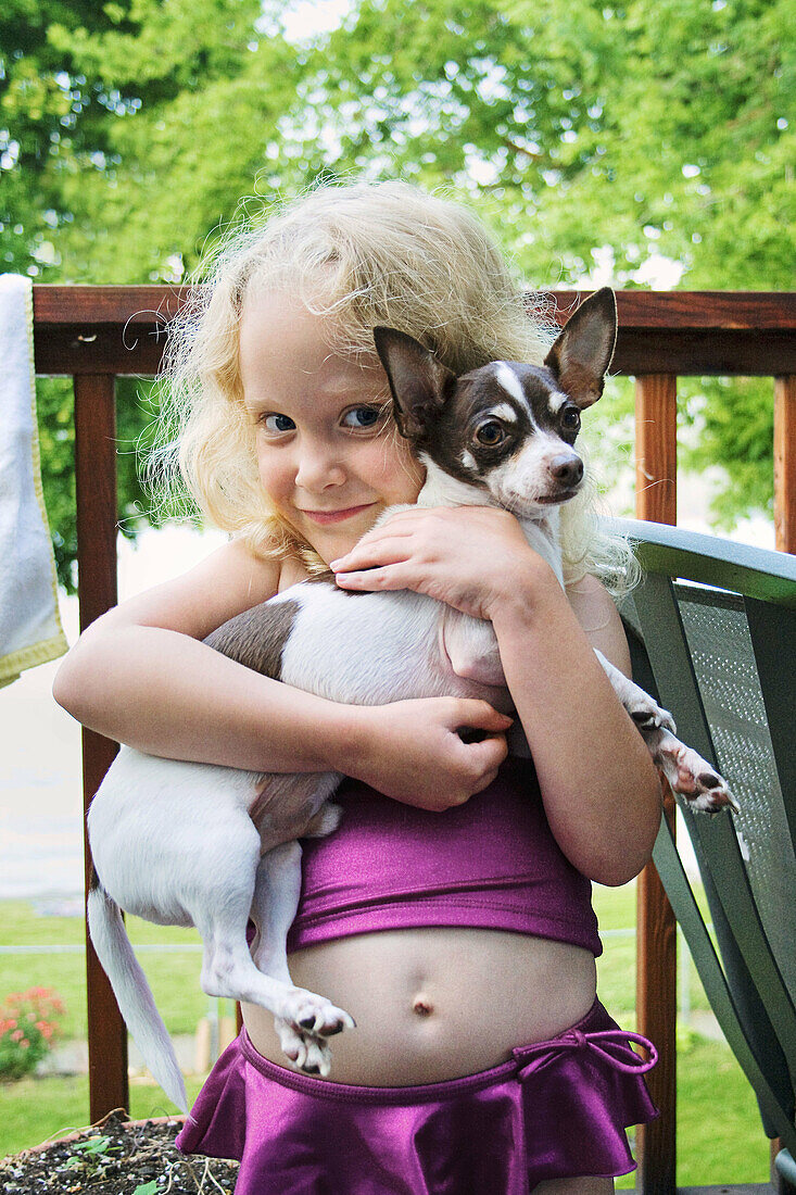 A Caucasian girl, 5-10, holds a Chihuahua