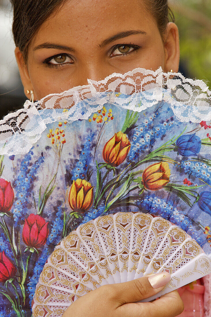 A portrait of a young girl posing with a colorful fan.