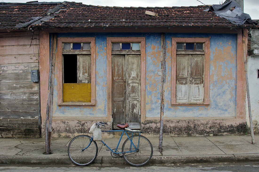 A bicycle parked in front of a funky small house.