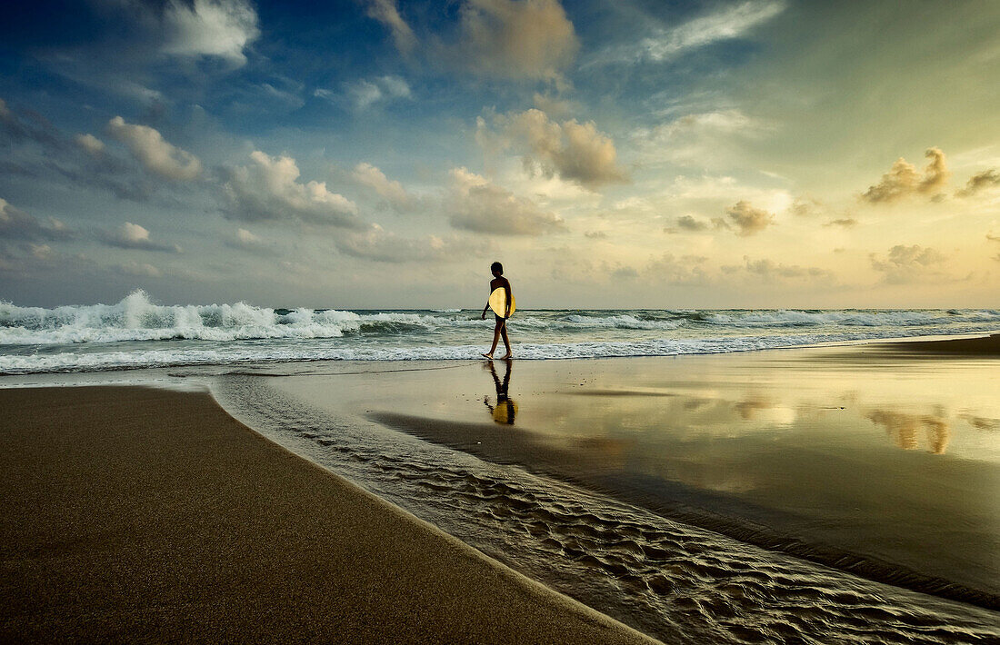 Joven surfista caminando por la orilla del mar