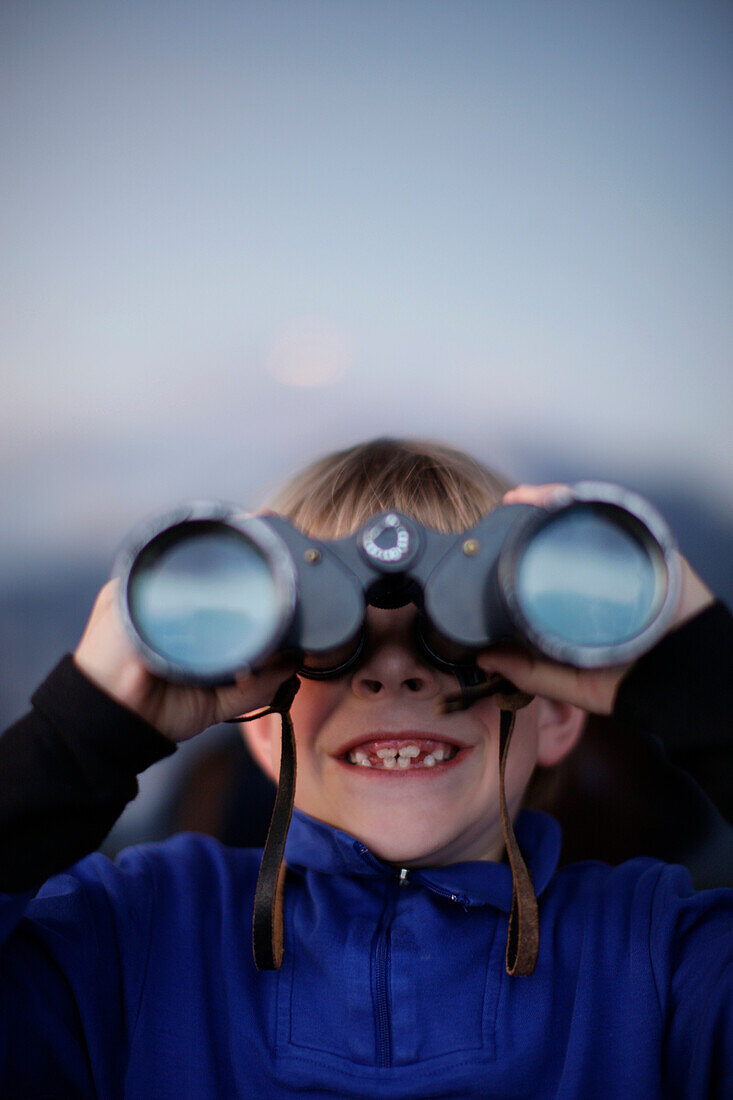 Boy (7 years) looking through binoculars, Brixen, Tyrol, Austria