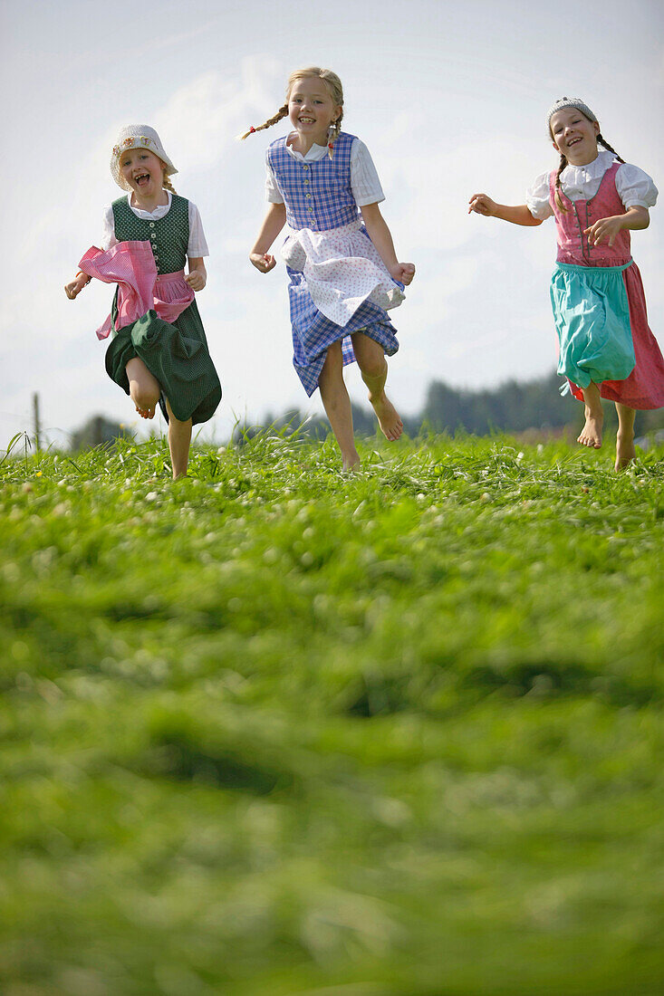 Three girls wearing dirndl in a meadow, Muensing, Bavaria, Germany