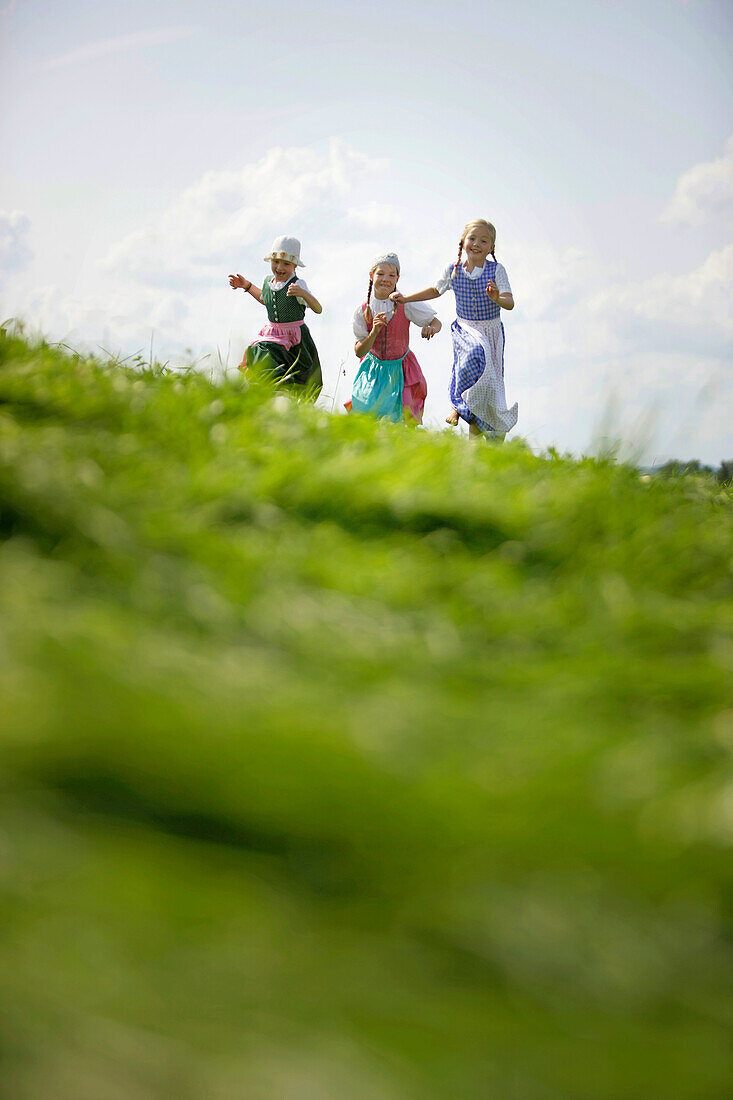 Drei Mädchen in Dirndl auf einer Wiese, Münsing, Bayern, Deutschland