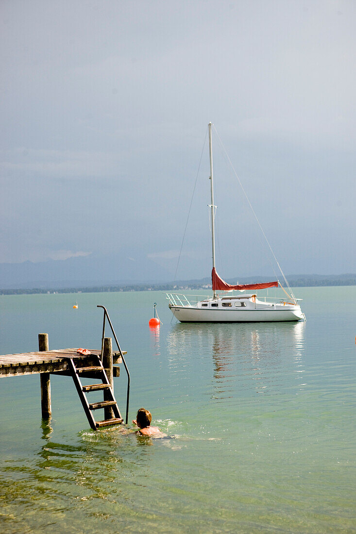 Person an einem Steg, Segelboot im Hintergrund, Starnberger See, Bayern, Deutschland