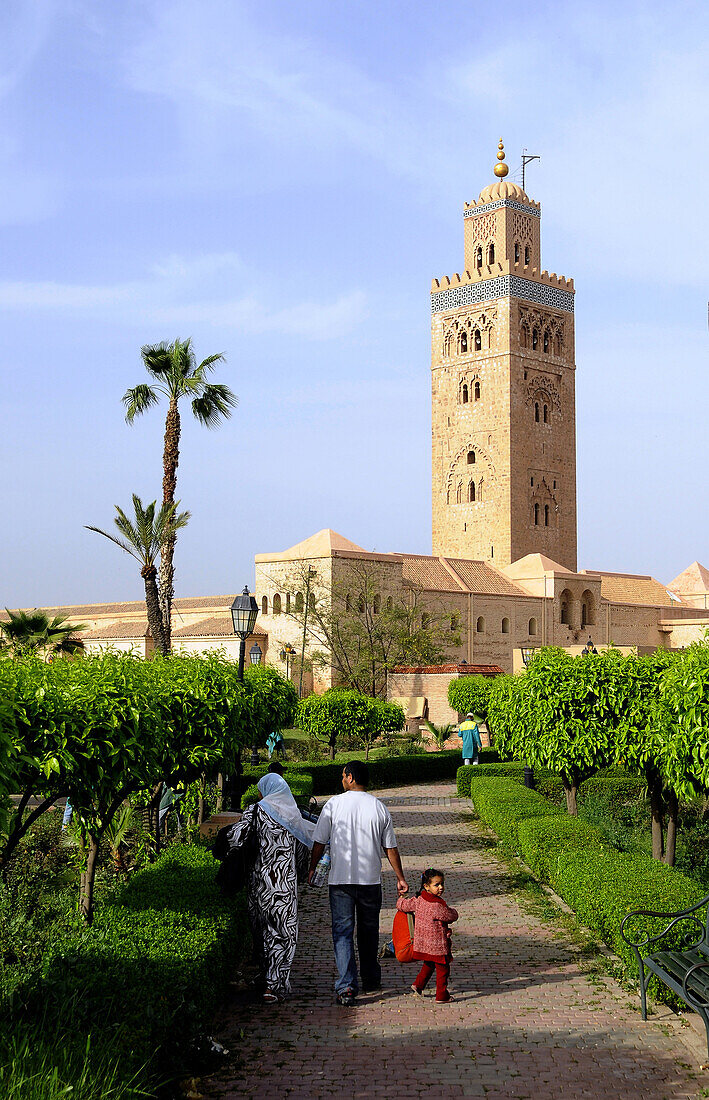 Familie in einem Park vor dem Minarett der Koutoubia Moschee, Marrakesch, Süd Marokko, Marokko, Afrika