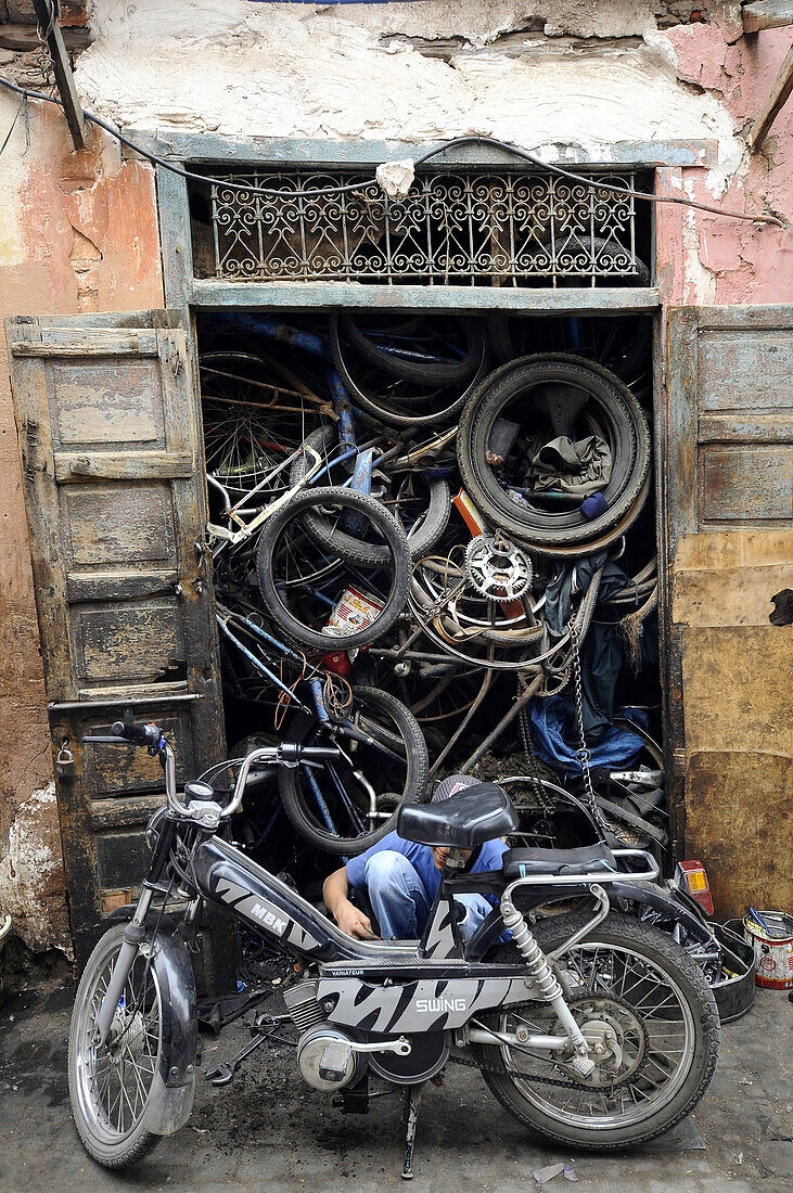 A man repairing a moped at the Souk at the Medina of Marrakesh, South Morocco, Morocco, Africa