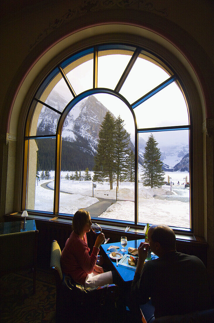 People in the lounge enjoying the view of Lake Louise, Fairmont Chateau Lake Louise, Alberta, Canada