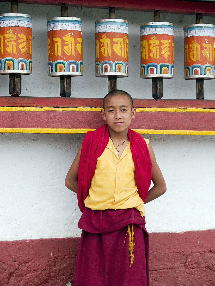 monk standing next to prayer wheels at the Phodong Monastery in Sikkim