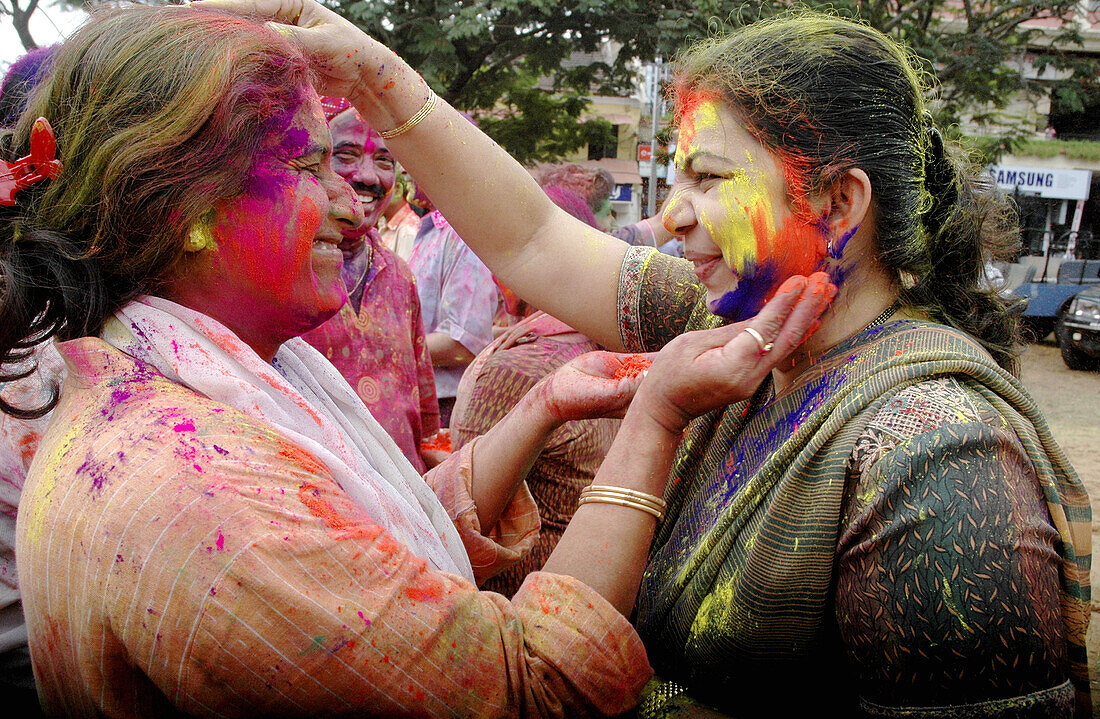 Panjim Goa, India, women putting colored powder on their faces during the Holi feast