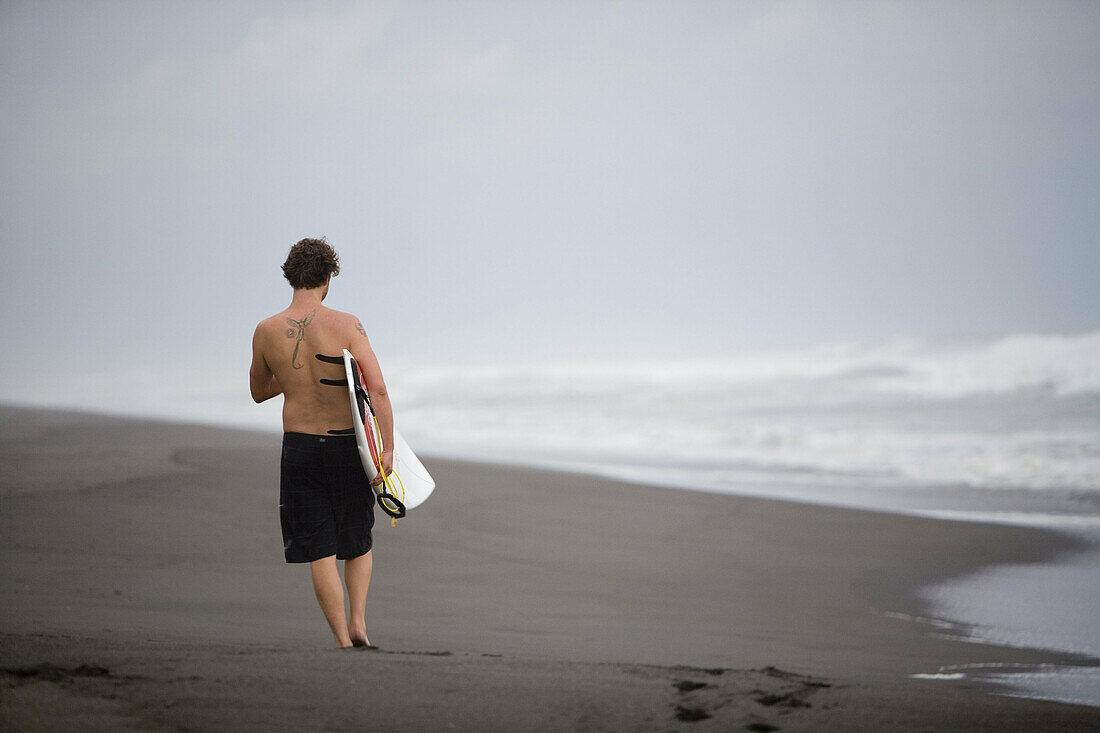 Guatemala, Paredon beach, man with surfboard
