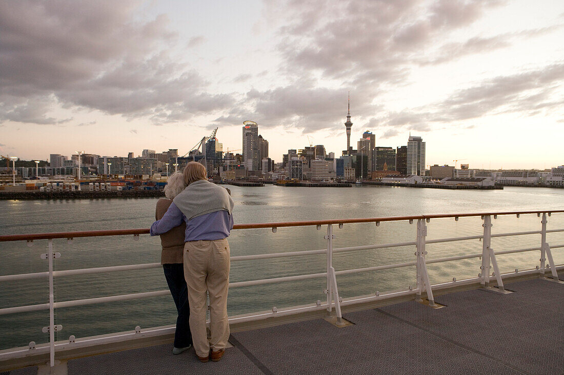 Paar blickt vom Kreuzfahrtschiff MS Columbus auf Skyline bei Sonnenuntergang, Auckland, Nordinsel, Neuseeland, Ozeanien