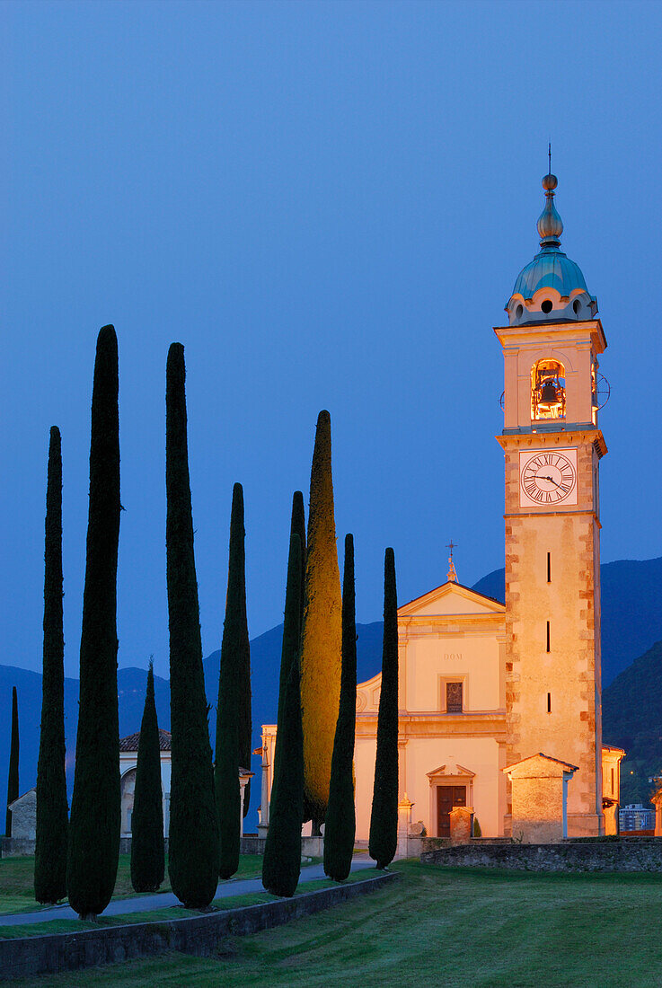 Illuminated church San Abbondino near Gentilino with cypress alley, Gentilino, Lugano, Ticino, Switzerland