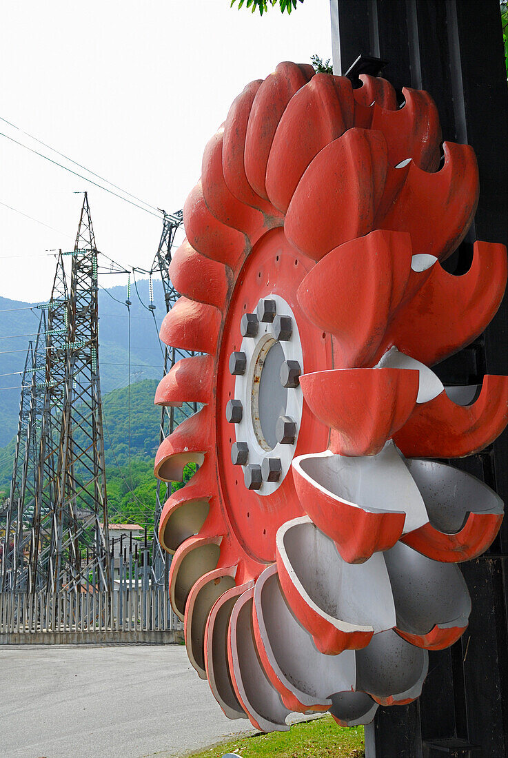 Rad einer Turbine mit Strommasten im Hintergrund, Peltonturbine, Wasserkraftwerk bei Chiavenna, Chiavenna, Lombardei, Italien