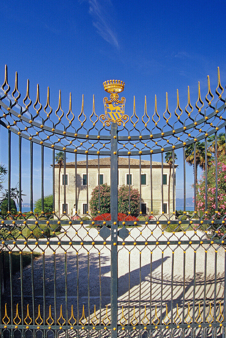 View through a gate at a mansion under blue sky, Punta San Vigilio, Lake Garda, Veneto, Italy, Europe