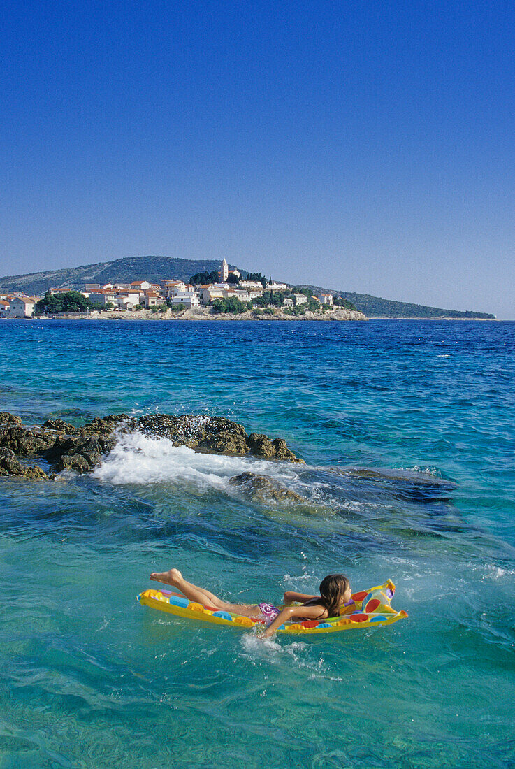 Mädchen auf Luftmatratze vor dem Strand von Primosten, Kroatische Adriaküste, Dalmatien, Kroatien, Europa