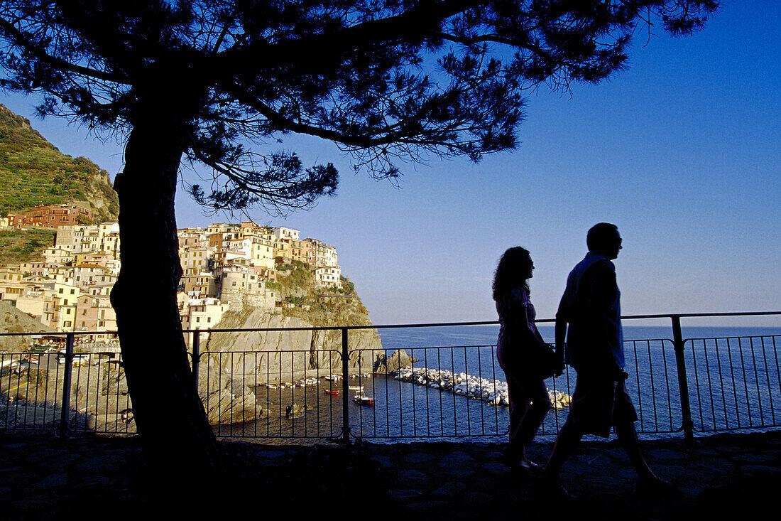 Paar geht Hand In Hand auf dem Wanderweg Via dell´Amore, Manarola im Hintergrund, Cinque Terre, Ligurien, Italienische Riviera, Italien, Europa