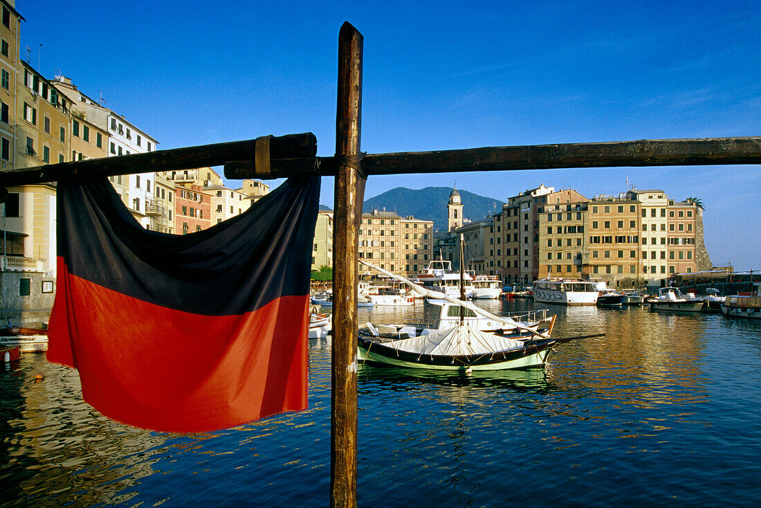 Black and red flag at the harbour under blue sky, Camogli, Liguria, Italian Riviera, Italy, Europe