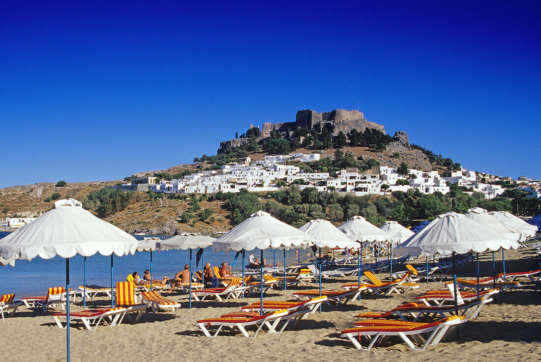 Blick auf Bucht mit Strand, Ort und Akropolis unter blauem Himmel, Lindos, Rhodos, Griechenland, Europa