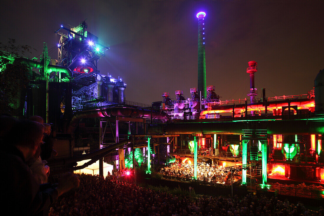 The Duisburg Philharmonic Orchestra playing in front of the illuminated backdrop of the Huette Meiderich, Duisburg, Ruhr Area, North Rhine-Westphalia, Germany, Europe