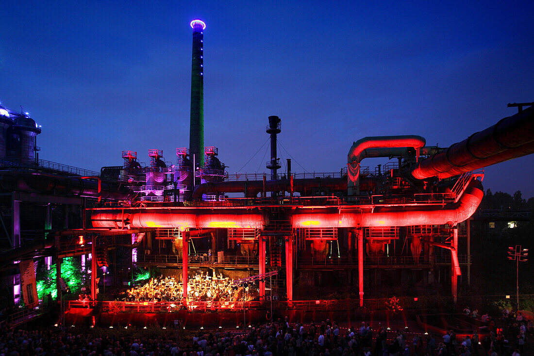 The Duisburg Philharmonic Orchestra playing in front of the illuminated backdrop of the Huette Meiderich, Duisburg, Ruhr Area, North Rhine-Westphalia, Germany, Europe