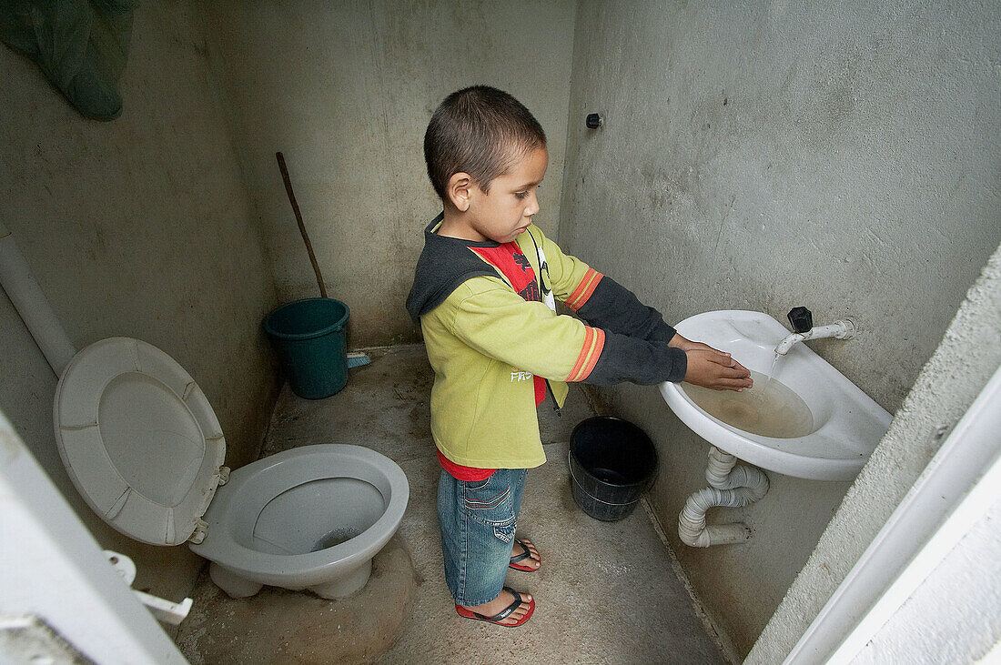Brazil  Boy washing his hands in new outside toilet funded by DEDAPP/IAF, Community of Serra da Cruz, near Pesqueira, Pernambuco