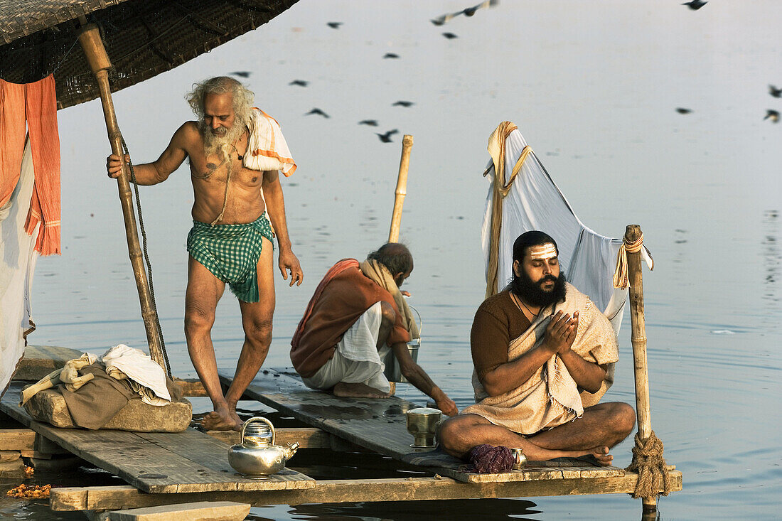 Man doing puja (Hindu devotional worship) by river Ganges at Kumba Mela festival