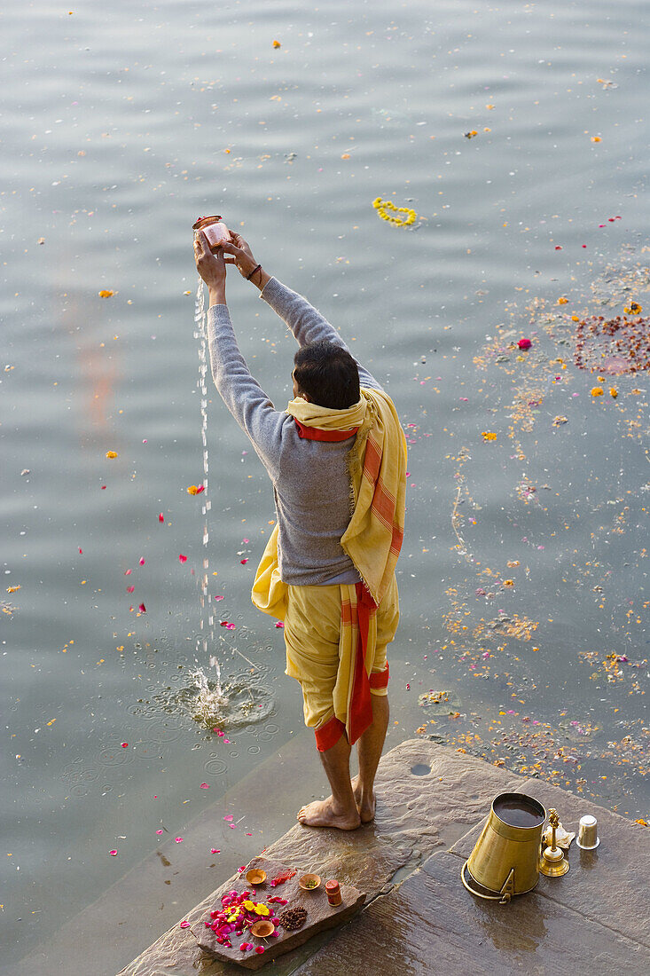 Pilgrim doing puja (Hindu devotional worship) in holy river Ganges, Varanasi, India