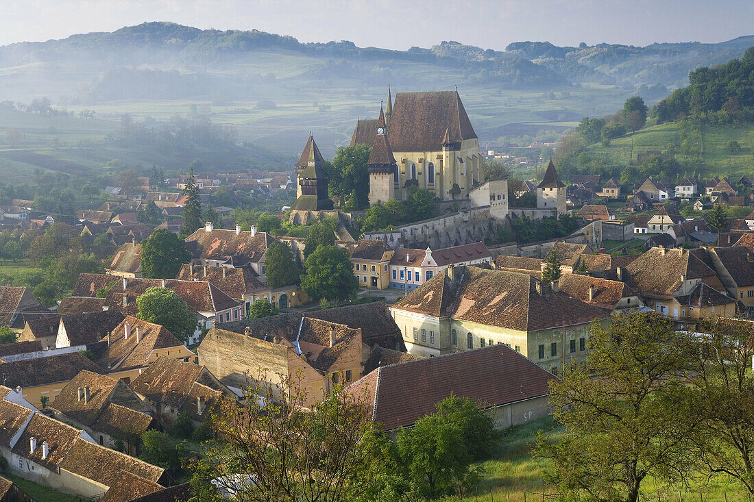 Biertan village with fortified church in morning mist. Romania