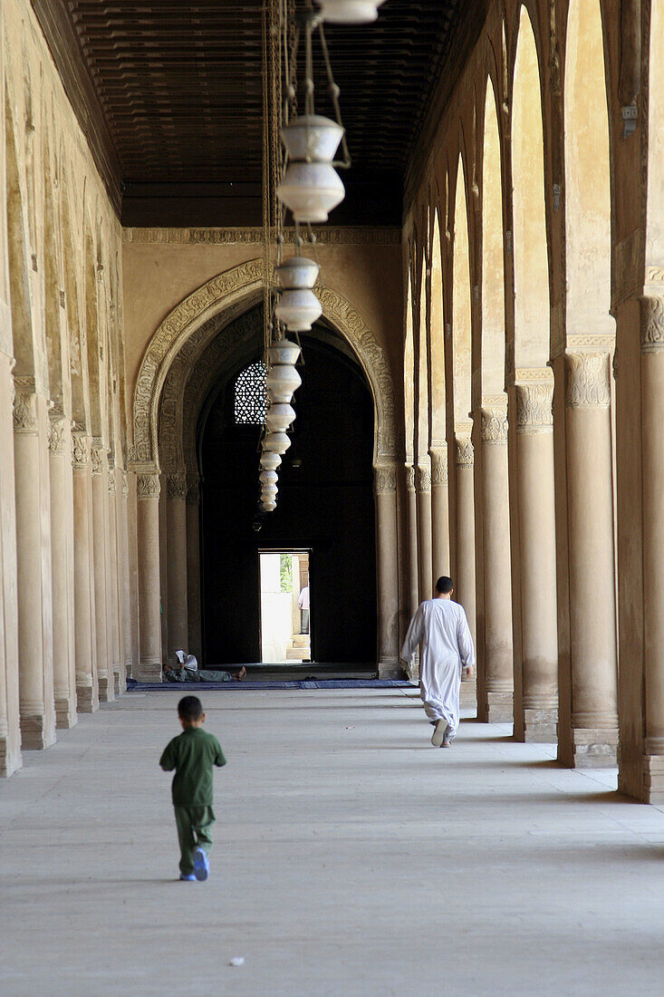 Man and boy walking inside Mosque of Ahamad ibn Tulun, Cairo, Egypt 