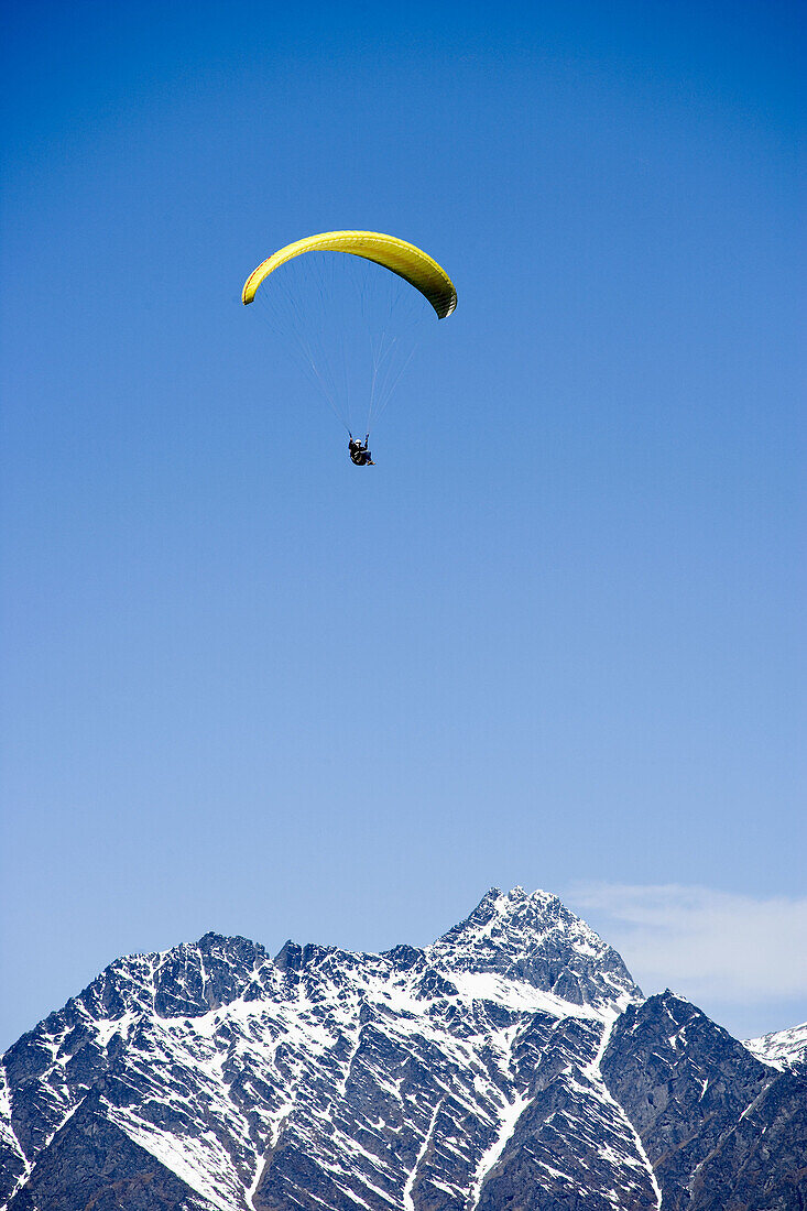 paraglider flying with snow covered mountains in background