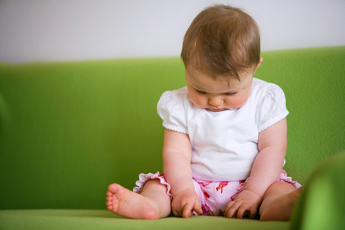 Baby (8 Monate) sitzt auf einer Couch, Wien, Österreich