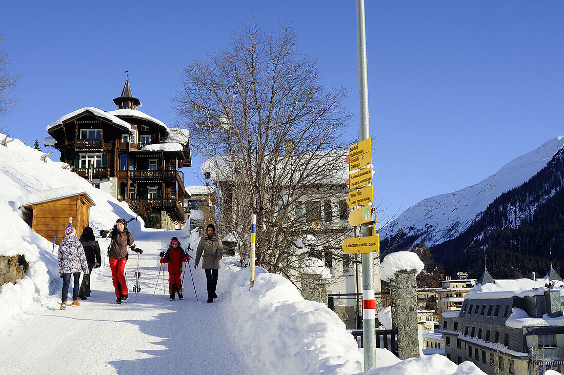Skifahrer auf verschneiter Straße, Davos, Graubünden, Schweiz