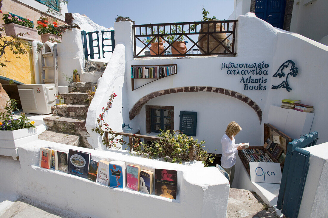 Frau im Buchladen Atlantis Books im Sonnenlicht, Oia, Santorin, Kykladen, Griechenland, Europa