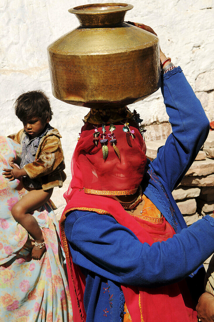 A big smile under the veil: a Rajasthani woman comes back home with fresh water pumped in the local well