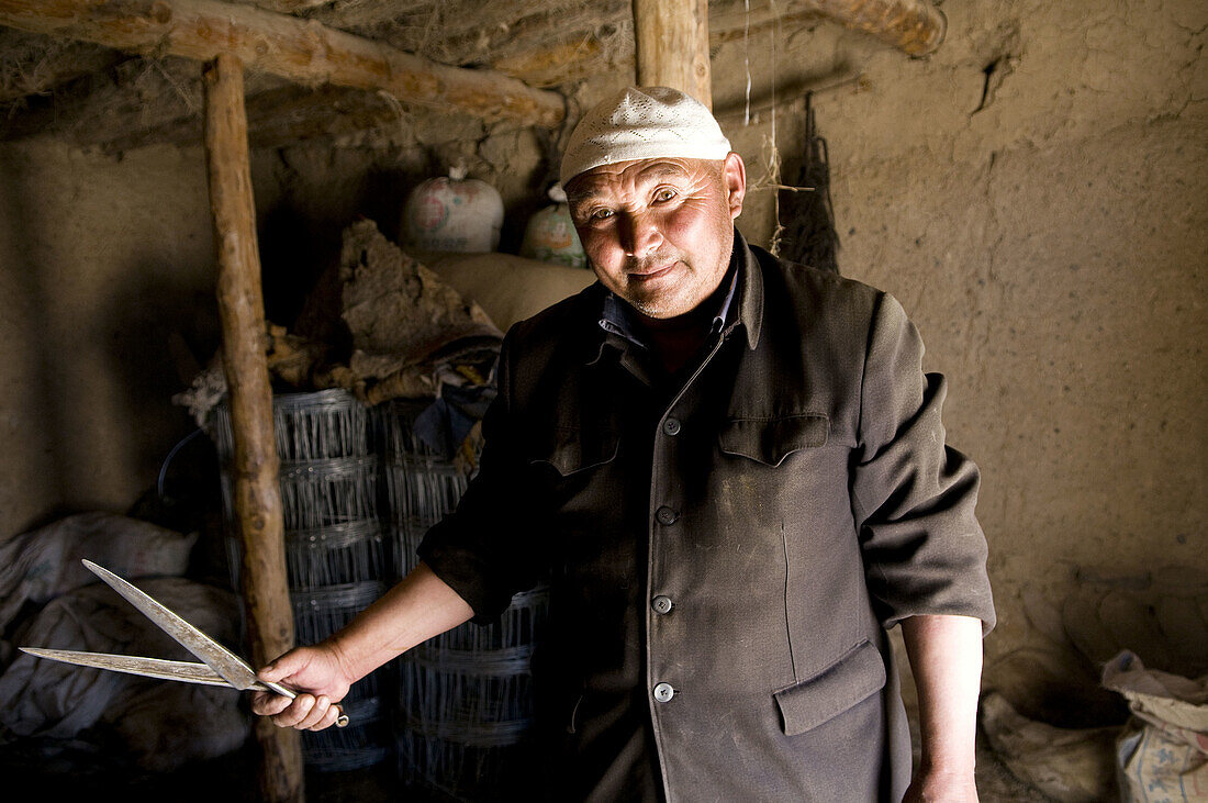 A friendly Kazakh man cuts down the wool of his sheep