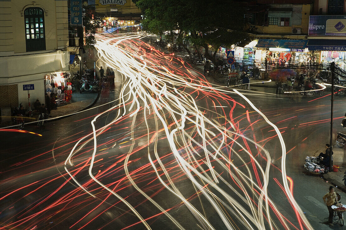 Chaotic traffic is illustrated by the streaking lights in this time exposure of a busy intersection in the Old Quarter, Hanoi, Vietnam