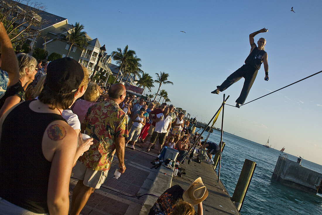 Acrobat performs on high wire with crowd watching.