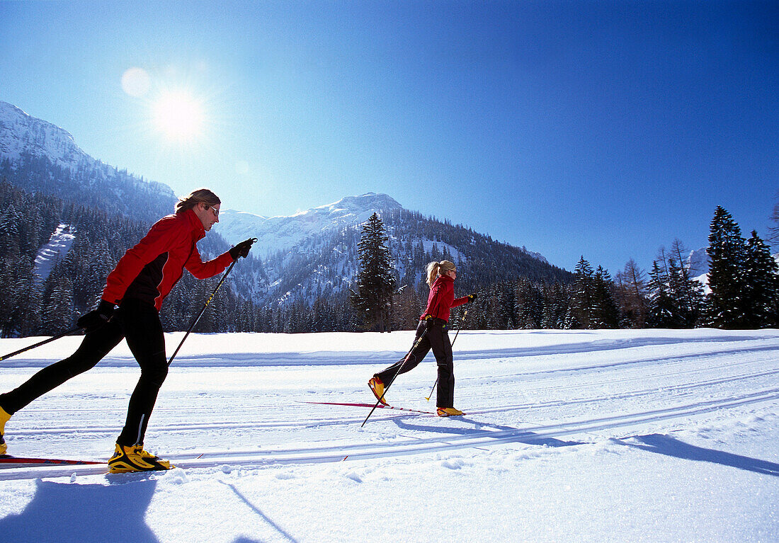 A couple cross-country skiing under blue sky, Tyrol, Austria, Europe