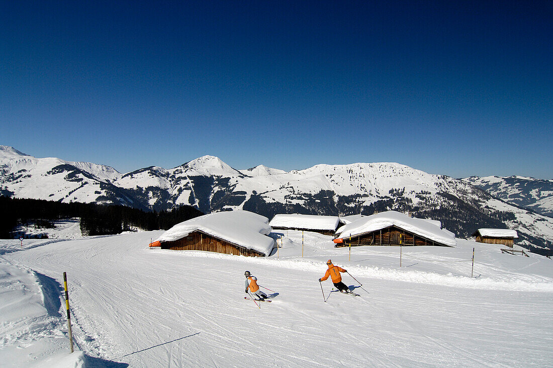 Skiers on a ski slope under blue sky, Kitzbuehel Alps, Tyrol, Austria, Europe